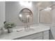 Stylish bathroom features a quartz countertop, round mirror, and a glass-enclosed shower at 5243 Wishing Arch Dr, Apollo Beach, FL 33572