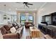 Bright living room featuring wood floors, leather couches, and large windows overlooking the backyard at 5243 Wishing Arch Dr, Apollo Beach, FL 33572