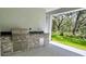 Outdoor kitchen featuring stainless steel grill, sink, stone counter and natural views at 13530 Oldenburg Dr, Hudson, FL 34667