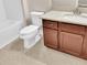 Bathroom with white fixtures, wood vanity, and tiled floor at 11522 Cambium Crown Dr, Riverview, FL 33569
