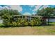 Mid-century modern home exterior with lush landscaping and a covered patio at 1702 Blind Pond Ave, Lutz, FL 33549