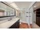 Modern bathroom featuring double vanity, walk-in shower with glass door, and wood look tile flooring at 2115 Seagull Dr, Clearwater, FL 33764