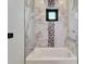 Elegant bathroom featuring a bathtub with shower and stylish marble-like and mosaic tile accents at 6540 Simone Shores Cir, Apollo Beach, FL 33572