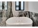 Close-up of a modern soaking tub with stylish marble accents and a window view at 6540 Simone Shores Cir, Apollo Beach, FL 33572