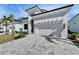 Side-view of the home featuring a paved driveway, minimalist landscaping, and a two-car garage at 6540 Simone Shores Cir, Apollo Beach, FL 33572