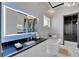 Modern bathroom with a bathtub, luxurious lighted mirror, dual vanity, and an entrance to a walk-in closet at 6542 Simone Shores Cir, Apollo Beach, FL 33572