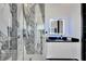 Modern bathroom featuring marble tile, a glass shower, and a sleek, illuminated mirror above the vanity at 6542 Simone Shores Cir, Apollo Beach, FL 33572