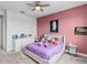 Charming bedroom with a pink accent wall, ceiling fan and dresser at 32588 Tree Of Life Ave, Wesley Chapel, FL 33543