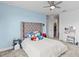 Light blue bedroom with a tufted headboard, ceiling fan, and walk-in closet at 32588 Tree Of Life Ave, Wesley Chapel, FL 33543