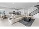 Open living room with sectional sofa, kitchen island, and staircase at 32588 Tree Of Life Ave, Wesley Chapel, FL 33543