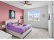 Bright bedroom with pink accent wall, ceiling fan and dresser at 32588 Tree Of Life Ave, Wesley Chapel, FL 33543