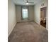 Neutral bedroom with a ceiling fan and a view into the bathroom, featuring carpet flooring and a window at 462 Spotted Slipper Pl, Ruskin, FL 33570