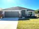 One-story home with gray siding, stone accents, and a two-car garage at 36188 Welsh Glade Rd, Dade City, FL 33525