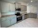 Modern kitchen with gray cabinets, granite counters, and stainless steel appliances at 36188 Welsh Glade Rd, Dade City, FL 33525