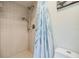 Tiled shower features adjustable shower head with a white and blue curtain next to a white toilet at 6605 Pemberton Sage Ct, Seffner, FL 33584