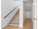 Bright staircase featuring natural wood steps, a black handrail, and white walls at 5006 W San Miguel St, Tampa, FL 33629