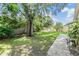 Landscaped backyard with stone walkway, mature tree, and lush lawn at 3501 Country Creek Ln, Valrico, FL 33596