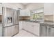 Well-lit kitchen features stainless steel appliances, granite countertops, white cabinets, and tile flooring at 3501 Country Creek Ln, Valrico, FL 33596