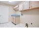 Laundry room with cabinets, wash sink, and modern tiled floors at 3501 Country Creek Ln, Valrico, FL 33596
