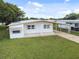 Single-wide mobile home with carport and grassy yard at 5353 Comanche St, Zephyrhills, FL 33542