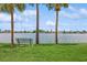 Scenic waterfront view with a park bench, lush greenery, and palm trees at 10426 La Mirage Ct, Tampa, FL 33615