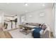 Bright living room boasts hardwood floors, a plush grey sofa, and seamless open-concept access to the modern, white kitchen at 9413 Ballaster Pointe Loop, Parrish, FL 34219