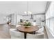 Open-concept dining area with a wooden table, white chairs, modern light fixture, and bright kitchen at 2509 N Glenwood Dr, Tampa, FL 33602