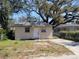 Modest single-story home with neutral stucco exterior and small front yard under the shade of mature trees at 4407 N 41St St, Tampa, FL 33610