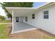 A covered back porch area overlooks a spacious yard with lush green landscaping, leading to back door at 801 Brodhag Dr, Punta Gorda, FL 33950