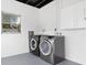 A well-lit laundry room showcasing modern, front-load washer and dryer units with white cabinets at 801 Brodhag Dr, Punta Gorda, FL 33950