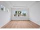 Bright bedroom featuring light wood floors, white walls and trim, and a large window with nice landscaping views at 8320 Golden Beach Ct, Parrish, FL 34219