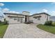Striking single-story home with modern architecture, three-car garage, and patterned brick driveway at 8320 Golden Beach Ct, Parrish, FL 34219