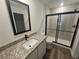 Modern bathroom with granite countertop vanity, framed mirror, and shower with black-framed glass door at 3769 S Haberland Blvd, North Port, FL 34288