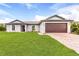 Single-story home with a two-car garage and a lush green lawn at 12564 Feldman Ave, Port Charlotte, FL 33981
