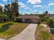 Aerial view of yellow house with driveway and palm trees at 1402 Viscaya Dr, Port Charlotte, FL 33952