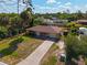 Aerial view of yellow house with palm trees, driveway, and neighboring houses at 1402 Viscaya Dr, Port Charlotte, FL 33952