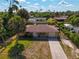 Aerial view of yellow house with palm trees, driveway, and neighboring houses at 1402 Viscaya Dr, Port Charlotte, FL 33952