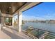 A covered balcony with a metal railing features views of the water, docks and neighborhood homes at 831 Bay Point Dr, Madeira Beach, FL 33708