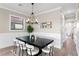 Elegant dining room with a modern chandelier, black table, and white chairs, complemented by wainscoting at 831 Bay Point Dr, Madeira Beach, FL 33708