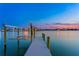 Dock with boat lift extends into the calm water during sunset, with waterfront homes in the background at 831 Bay Point Dr, Madeira Beach, FL 33708