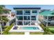 Contemporary home featuring multiple balconies, outdoor seating, pool, and well-manicured landscaping at 831 Bay Point Dr, Madeira Beach, FL 33708