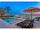 Backyard pool with waterfront view, featuring lounge chairs and a large sun umbrella for relaxation at 831 Bay Point Dr, Madeira Beach, FL 33708