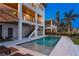 Backyard pool and stairs leading to upper levels of home, along with patio seating area underneath balconies at 831 Bay Point Dr, Madeira Beach, FL 33708