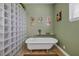 Elegant bathroom with clawfoot tub, glass block accents, and vintage art at 429 Flamingo Dr, Apollo Beach, FL 33572