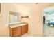 Bathroom with wood cabinets, large mirror and a view into the main bedroom at 228 Star Shell Dr, Apollo Beach, FL 33572