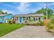Inviting single-story home with a vibrant blue door, complemented by lush landscaping and driveway at 2866 15Th N Ave, St Petersburg, FL 33713