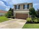 Two-story house with brown garage door and landscaping at 228 Star Shell Dr, Apollo Beach, FL 33572
