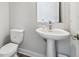 Modern half-bathroom featuring a pedestal sink, chrome faucet, and white toilet for a clean look at 2909 W Spruce St, Tampa, FL 33607