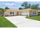 Tan house with white trim, attached garage, and landscaped lawn at 2476 Grove Ridge Dr, Palm Harbor, FL 34683