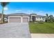 Beautifully landscaped, single-story home with a three-car garage and paver driveway under a bright, sunny sky at 10385 Sunday Dr, Port Charlotte, FL 33981